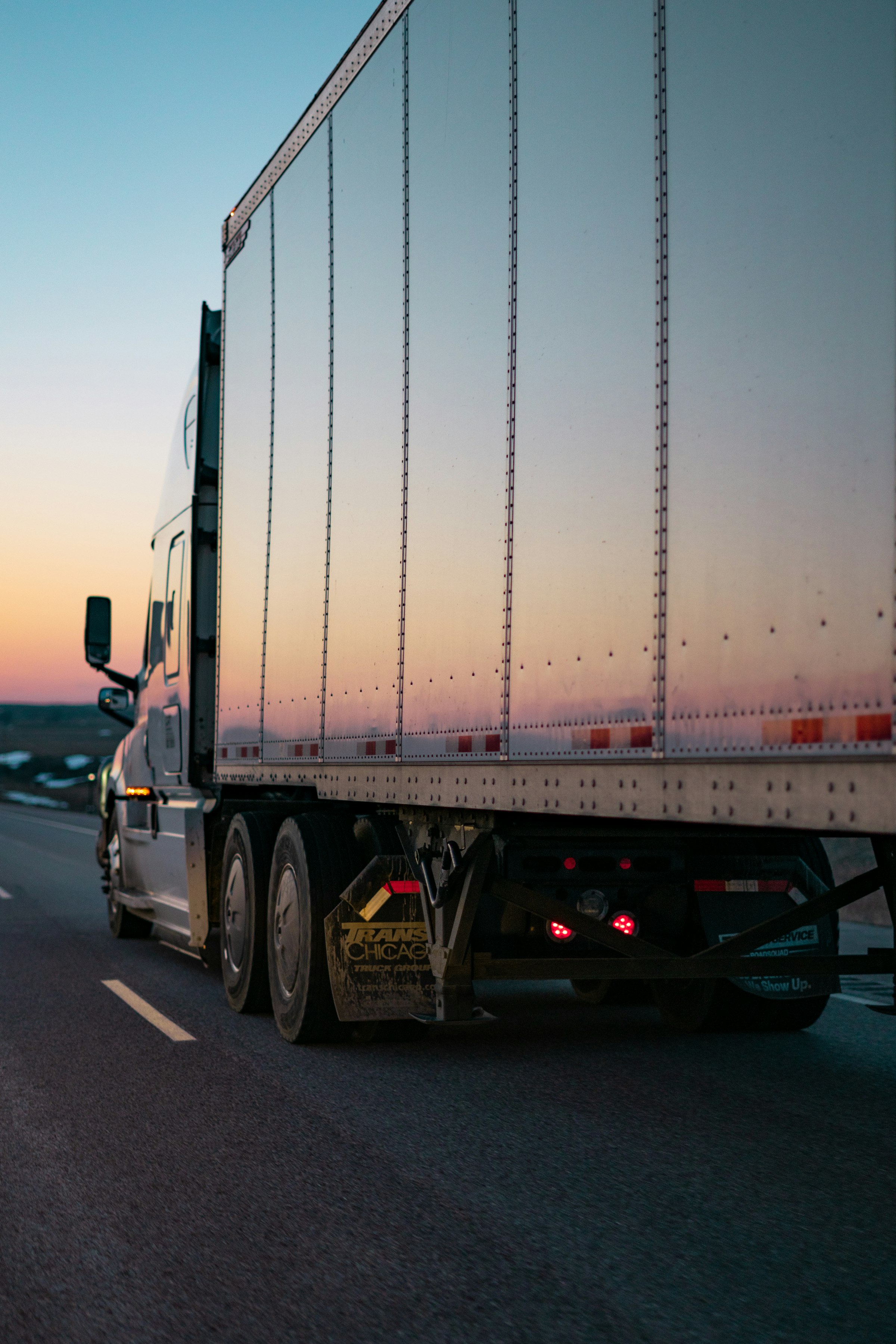 Semi-truck hauling freight down a Southern California highway at sunset